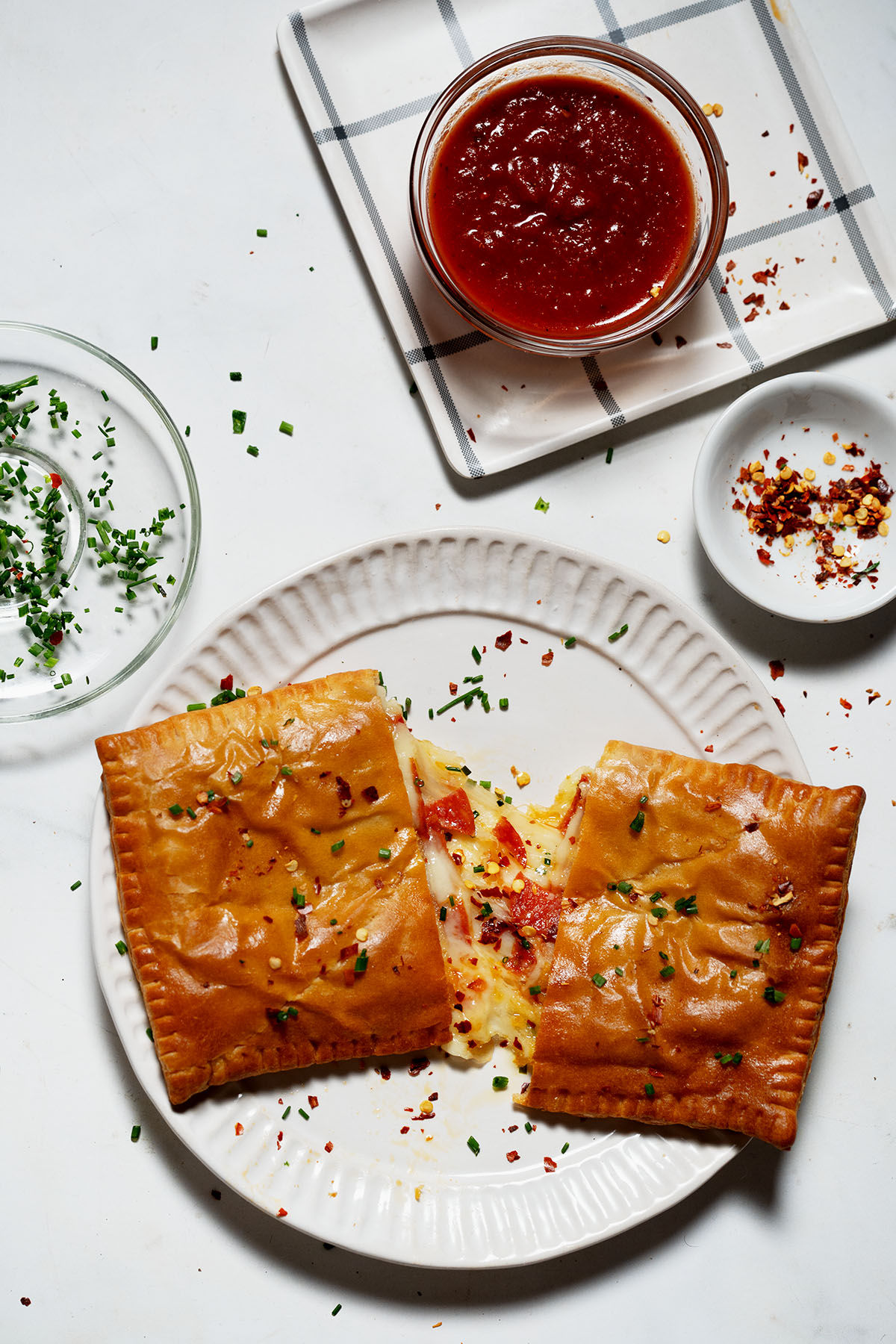 Air Fryer Pizza Pocket cut in half with cheese pull on a white plate. 