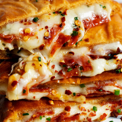 Golden brown pizza pockets stacked on a plate with dipping sauce