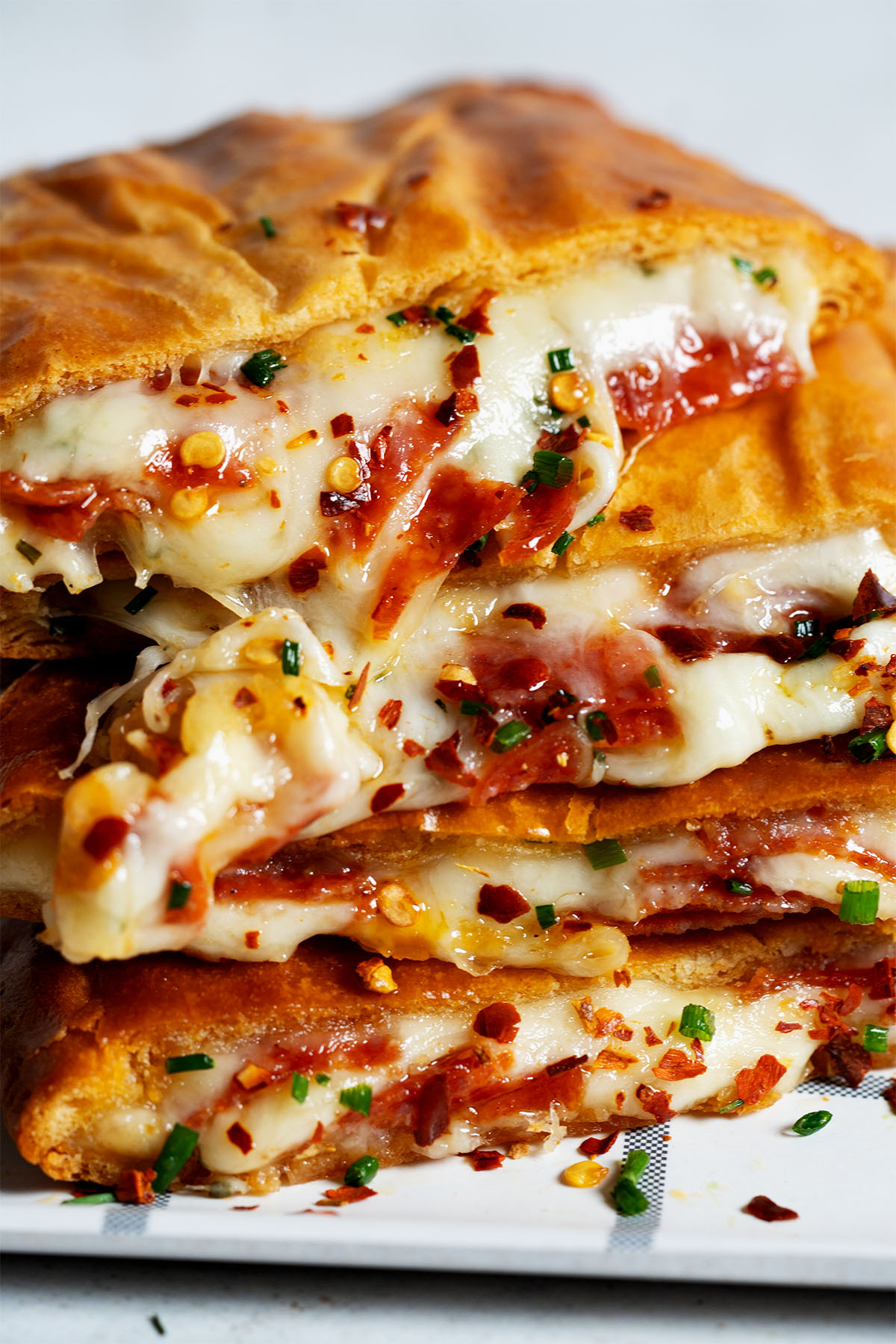 Golden brown pizza pockets stacked on a plate with dipping sauce