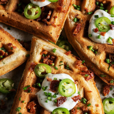 Crispy bacon cheddar savory waffles topped with sour cream, jalapeño slices, chives, and crumbled bacon.
